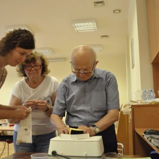 Seniorzy pod opieką pani Kingi wykonują kolorowe witraże