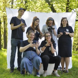 Pięcio wolontariuszy stoi w parku na tle rozwieszonego na drzewach białego płótna