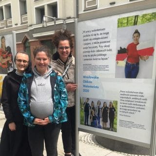 Trzy wolontariuszki przy tablicy wystawowej prezentującej Fundację FONIS