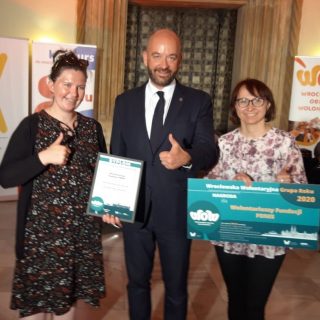 Dwie wolontariuszki Fundacji FONIS trzymają nagrody. Między nimi Prezydent Wrocławia - Jacek Sutryk