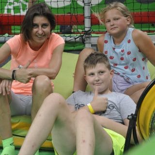 Dwójka dzieci z panią wychowawczynią siedzi w parku trampolin