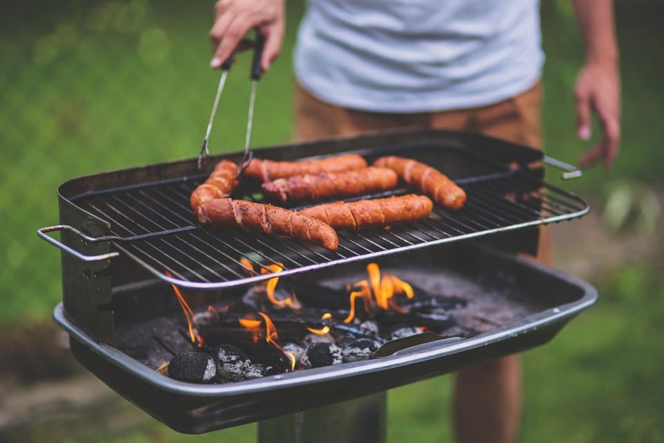 Grill na koniec wakacji Osoba szczypcami przekłada kiełbasę na grillu