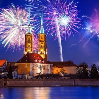 Wrocławska katedra nocą, niebo rozświetlają fajerwerki