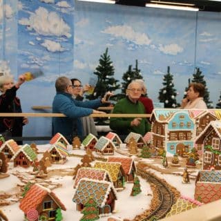 Seniorzy oglądają dekorację miasteczka zrobionego z piernika