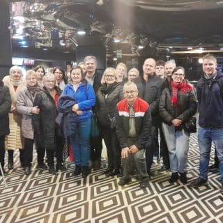 Zdjęcie grupowe około 30 osób pozujących do zdjęcia na dywanie w romby