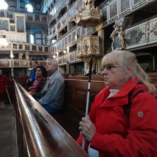 Kobieta z białą laską siedzi w zabytkowym kościele