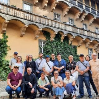Zdjęcie grupowe kilkunastu osób na tle zamkowych krużganków