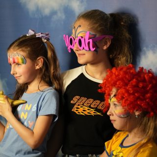 Trzy dziewczynki kolorowych strojach pozują do zdjęcia
