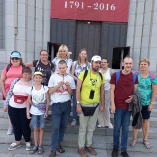 Grupa osób na schodach prowadzących do kościoła pozuje do zdjęcia