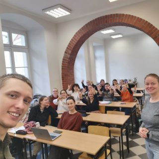 Mężczyzna robi selfie w tle grupa studentów w sali wykładowej