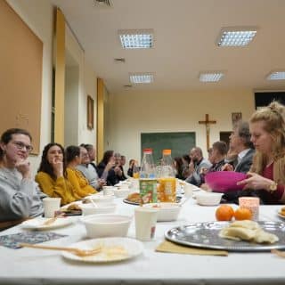 Ludzie siedzą po obu stronach świątecznego długiego stołu