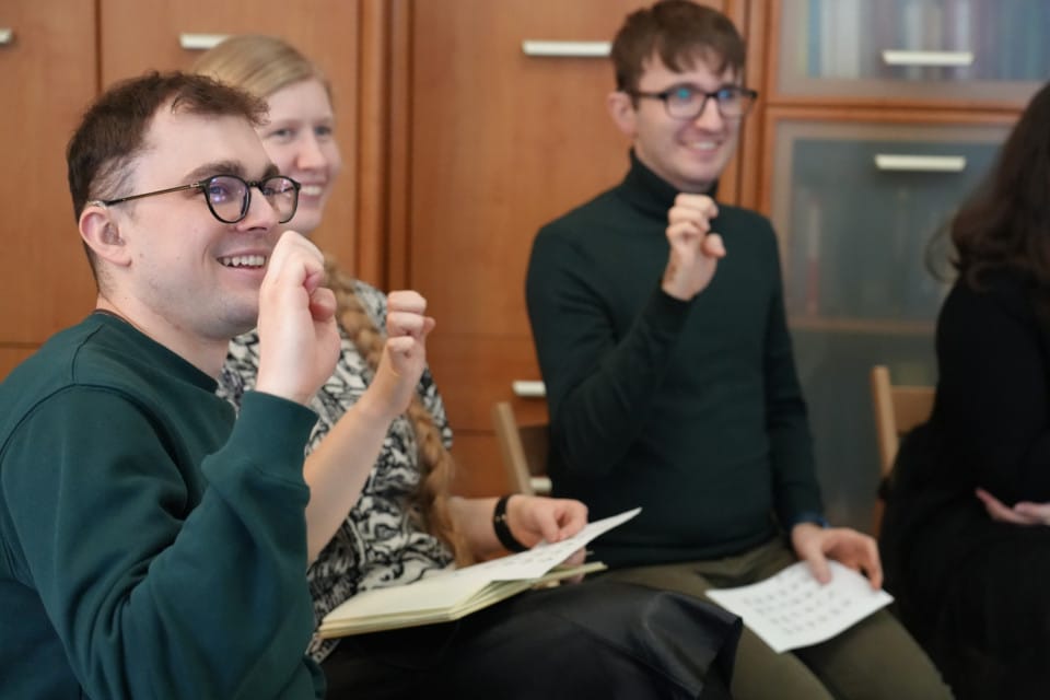 Międzynarodowy język migowy Trzy uśmiechnięte osoby pokazują znaki alfabetu migowego