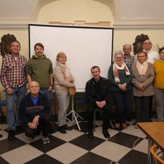Zdjęcie grupowe kilkunastu osób w sali