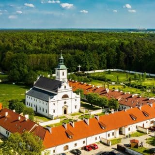 Kościół otoczony zabudowaniami klasztornymi na skraju lasu